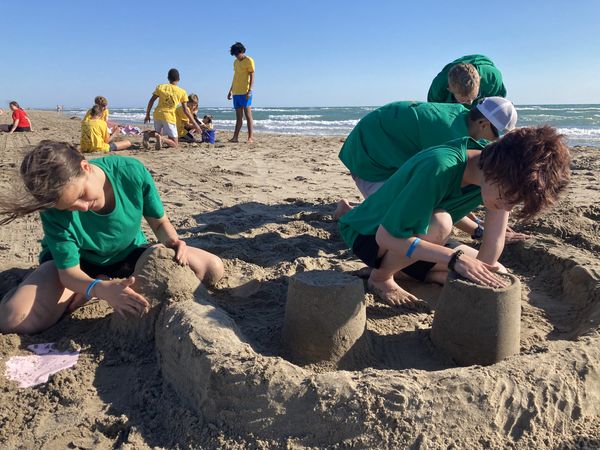Jugendliche bauen eine Sandburg am Meer